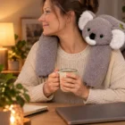 Kobieta przy biurku z zamkniętym laptopem, na jej barkach leży koala Otulak, w ręku kubek herbaty
