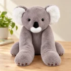 Otulak, koala 60 cm z długimi łapkami, na kremowym tle, obok książka obrazkowa i kredki w słoiku